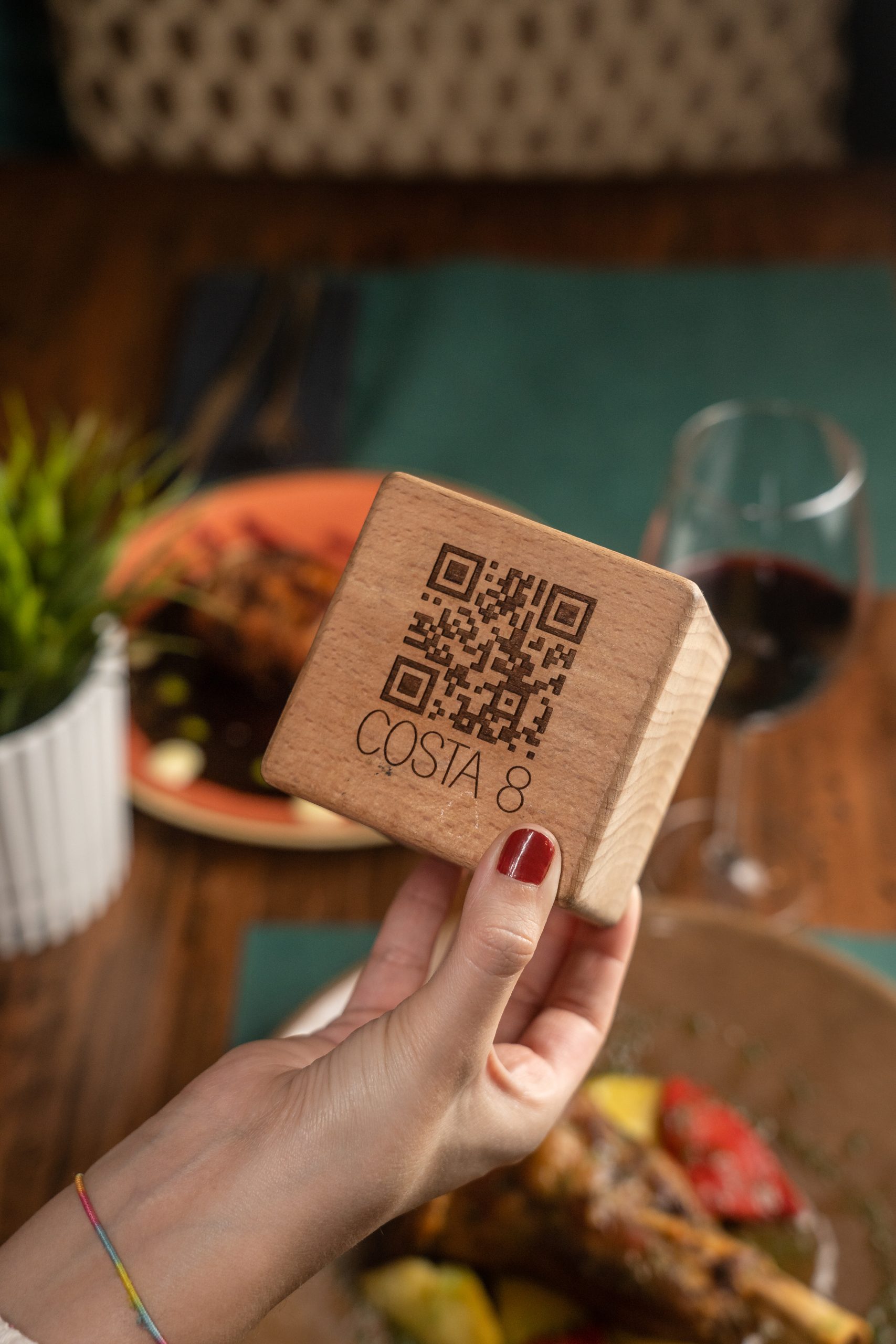 Mano sosteniendo una tarjeta con código QR de Costa 8 sobre la mesa